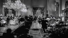 an old black and white photo of people dancing in a ballroom with chandeliers