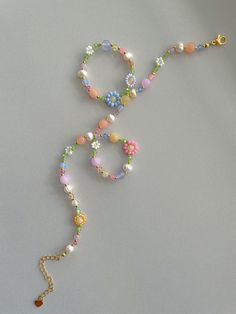 a multicolored beaded necklace on a white surface with a gold chain and clasp