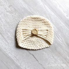 a crocheted hat with a bow on the side sitting on a marble floor