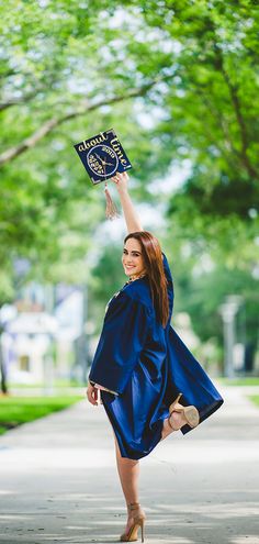 a woman in blue graduation gown holding up her diploma