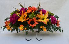 an arrangement of colorful flowers in a vase with metal stand legs on a white background