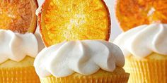 three cupcakes with frosting and orange slices on top