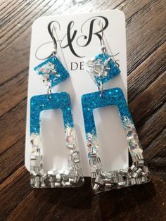 the earrings are made with blue and silver glitters on them, which is attached to an acrylic earring