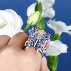 Our gorgeous flying butterfly ring, with its distinctive workmanship, pays tribute to the glamour and elegance of this creature. Through its graceful movement between your fingers, it recreates the fluttering charm of wings and adds unique enchantment to your femininity. Combing beautiful colors and asymmetry, this dazzling piece highlights eight brilliant marquise-cut blue stones, and smaller round stones in purple paved on wings. The multi-colored butterfly, fashioned in fine sterling silver, Luxury Butterfly White Gold Jewelry, Luxury Butterfly Shape White Gold Jewelry, Luxury Butterfly Shaped White Gold Jewelry, Luxury White Gold Butterfly Jewelry, Luxury White Gold Butterfly Ring, Silver Jewelry With Butterfly Charm, Elegant Wing-shaped Butterfly Charm Jewelry, Elegant Butterfly Charm Jewelry, Elegant Wing-shaped Jewelry With Butterfly Charm