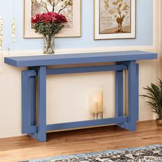 a blue console table with flowers on top and candles in the vase next to it