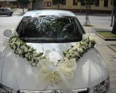 a white car decorated with flowers and ribbons