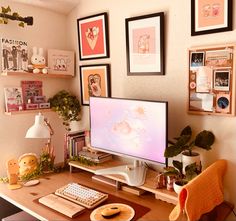 a desk with a computer monitor, keyboard and various pictures on the wall above it