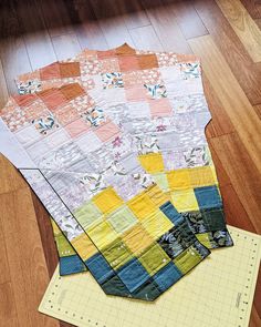 four pieces of quilt sitting on top of a piece of yellow and blue paper next to a ruler