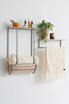 a towel rack with two towels hanging on it and a potted plant next to it