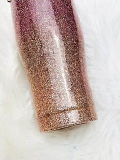 a pink and gold glitter tumbler sitting on top of a white fur covered floor