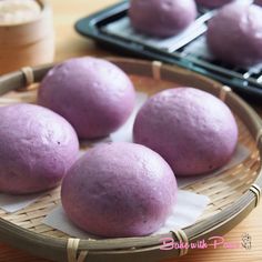 some purple balls are in a basket on a table next to muffin tins