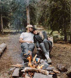 two people sitting next to each other in front of a campfire