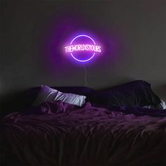 a purple neon sign that reads the ridiculous ones on it's wall above a bed