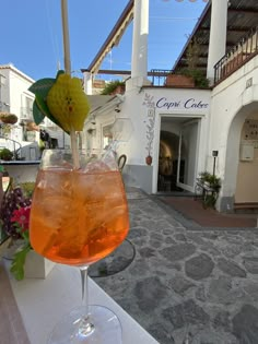 a glass filled with liquid sitting on top of a table next to a white building