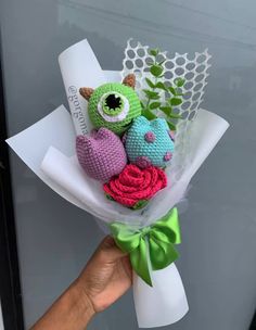 a hand holding a bunch of stuffed animals in it's palm with greenery