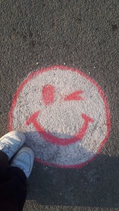 someone standing in front of a smiley face painted on the ground