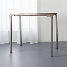 an empty table in front of a white brick wall with curtains on the window sill