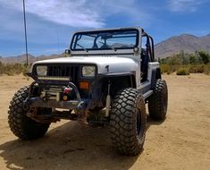 a white jeep is parked in the desert