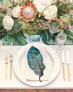 a place setting with flowers and greenery on the table