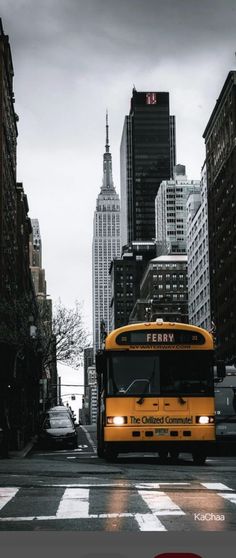 a yellow school bus driving down a street next to tall buildings in new york city