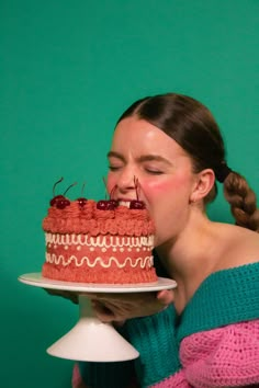 a woman biting into a cake with cherries on it