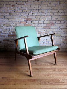 a green chair sitting on top of a wooden floor next to a brick wall in a room