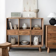 a wooden shelf filled with lots of different types of items next to a chair and table