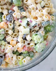 a bowl full of pasta salad with broccoli and blueberries