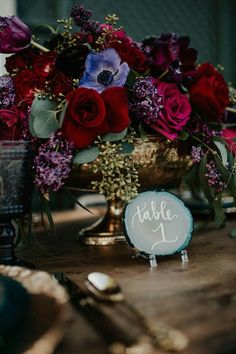 a table topped with a vase filled with red and purple flowers