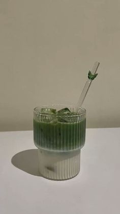 a glass filled with green liquid on top of a white table