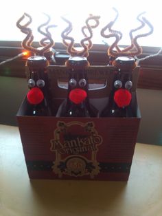 four bottles of beer sitting on top of a wooden table next to a lit window