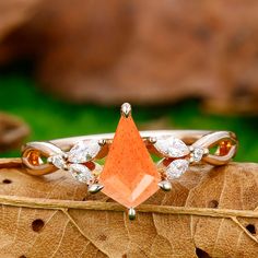 an orange diamond ring sitting on top of a leaf