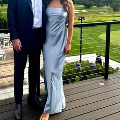 a man and woman standing on a deck in front of a green golf course with mountains behind them