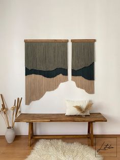 two wall hangings on the wall above a wooden table with a white rug in front of it