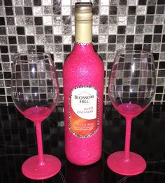 two wine glasses next to a bottle of pink wine on a black table with mosaic tiles in the background