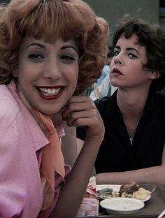 two women sitting at a table with plates of food