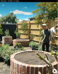 a man standing next to a garden filled with lots of dirt and plants on top of it