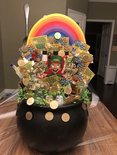 a pot filled with lots of money sitting on top of a wooden table next to a rainbow