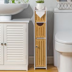 a white toilet sitting next to a wooden cabinet