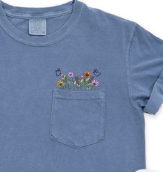 Comfort Colors Embroidered crewneck wildflower pocket tshirt. Embroidered flower shirt. Flower Boho Shirt. Gift for her or Girlfriend Gift. PLEASE NOTE THAT THE PICTURES ON THE LISTING ARE SAMPLES ONLY. If interested in adding embroidery to the sleeve please go to this listing: https://www.etsy.com/listing/1674502020 Because it is made to order, we don't accept the return or exchange unless we make a mistake We are unable to replace or refund purchases based on the color and the font selections. Cute Spring Tops With Pockets, Spring T-shirt With Pockets And Relaxed Fit, Cotton Crew Neck Top With Embroidered Patch, Blue Relaxed Fit T-shirt With Floral Embroidery, Cute Crew Neck Top With Pockets, Blue Tops With Custom Embroidery For Spring, Casual Tops With Embroidered Patch For Spring, Casual Spring Tops With Embroidered Patch, Cute Blue Tops With Pockets