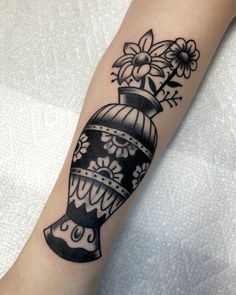 a black and white tattoo with flowers on the arm, which has a bell in it