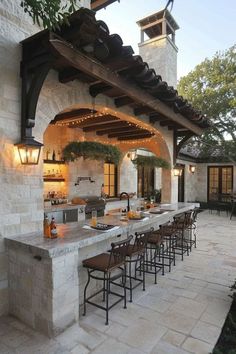 an outdoor kitchen with lots of counter space and lights hanging from the roof over it