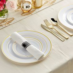 the table is set with gold and white plates, silverware, and napkins