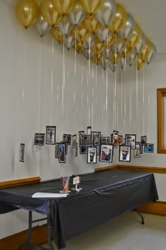 balloons are hanging from the ceiling above a long table with pictures on it and photos below