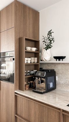 a coffee maker is sitting on the counter in this modern kitchen with wood cabinets and white walls