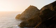 two large rocks sticking out of the ocean next to each other on top of a cliff