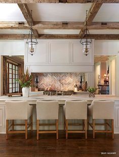 a large kitchen with white cabinets and wooden flooring, along with an island in the middle