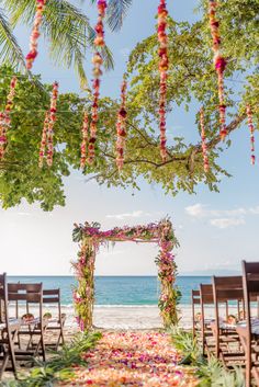 an outdoor ceremony set up at the beach with flowers and greenery on the aisle