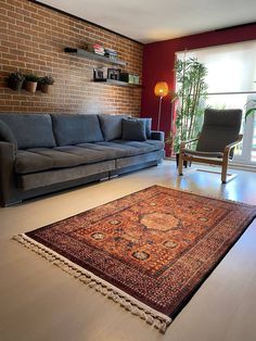 a living room filled with furniture and a large rug on the floor in front of a brick wall