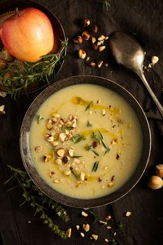 a bowl filled with soup next to an apple and nuts on top of a table